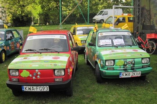 Zdobione Fiaty 126p w barwach nawiązujących do Ogólnopolskich Dni Pszczelarzy na trawie.