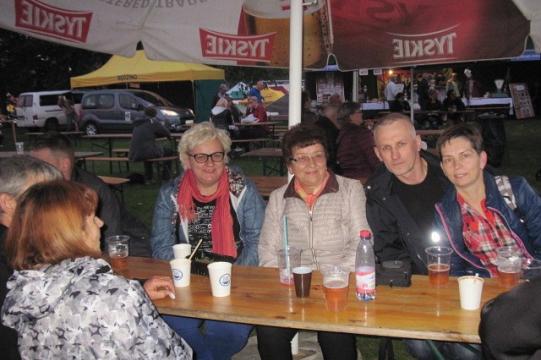Uczestnicy Dni Pszczelarzy przy stoliku delektują się napojami.