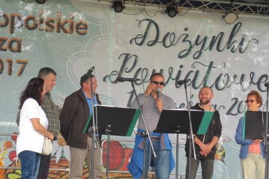 Uczestnicy na scenie z transparentem Ogólnopolskie Dni Pszczelarzy i Dożynki Powiatowe.