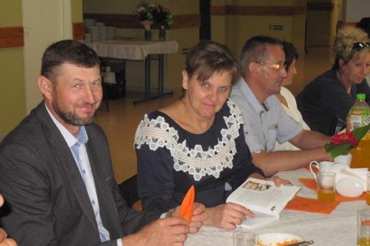 Uczestnicy obchodów Koła Pszczelarzy siedzą przy wspólnym stole.