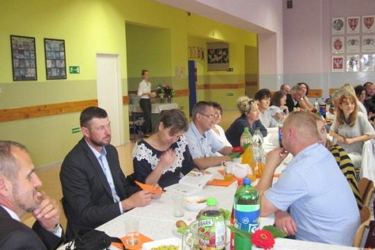 Uczestnicy obchodów 35-lecia Koła Pszczelarzy siedzą przy wspólnym stole.