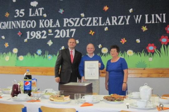 Jubileusz 35-lecia Koła Pszczelarzy w Lini z trzema osobami i dyplomem.