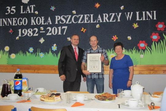 Trzy osoby z dyplomem na uroczystości 35-lecia Koła Pszczelarzy w Linii.