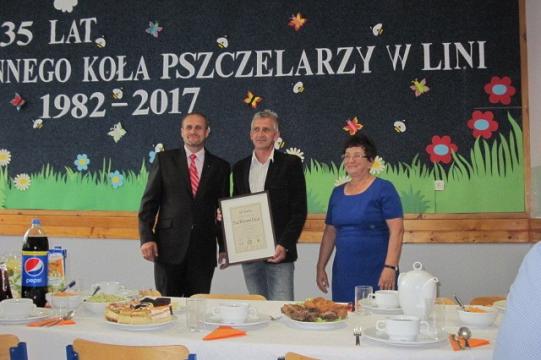 Trzy osoby z dyplomem na uroczystości 35-lecia Koła Pszczelarzy w Lini.