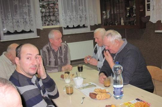 Mężczyźni uczestniczą w zimowym spotkaniu lub szkoleniu, siedząc przy stole z napojami.
