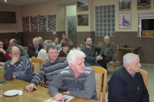 Uczestnicy zimowego spotkania lub szkolenia w sali, skupieni na prelekcji.