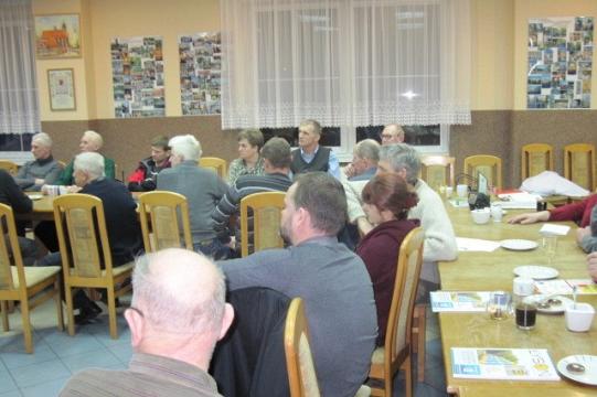 Uczestnicy zimowego spotkania lub szkolenia siedzą przy stołach w sali.