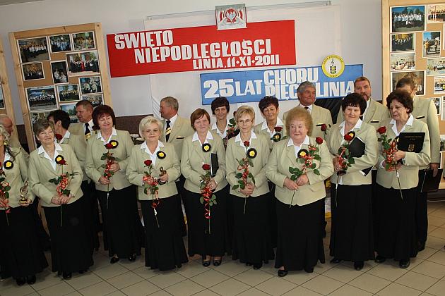 Członkowie Chóru Pięciolinia w strojach, pozujący grupowo na tle transparentu.