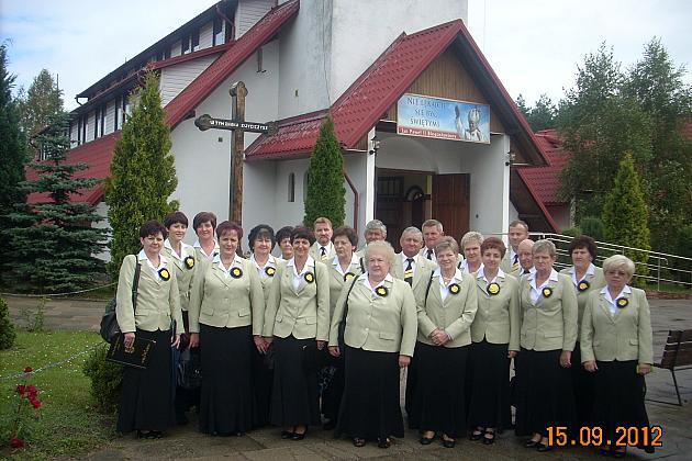 Grupa chórzystów Pięciolinia w jednolitych strojach przed świątynią.