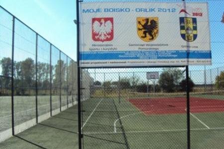 Boisko sportowe typu Orlik z banerem: MOJE BOISKO ORLIK 2012 i herbami.
