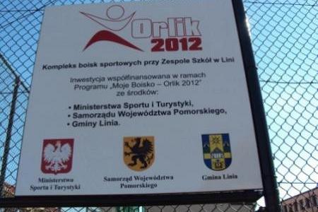 Tablica informacyjna projektu "Moje Boisko Orlik 2012" na siatce ogrodzeniowej.