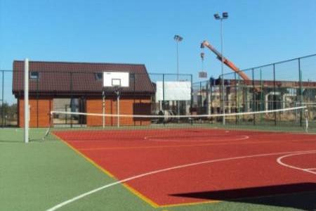 Boisko wielofunkcyjne Orlik 2012 z czerwoną i zieloną nawierzchnią sportową.
