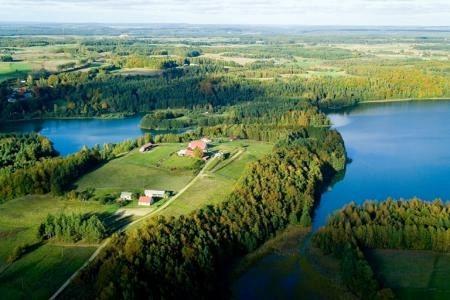 Lotniczy widok Gminy Linia: jezioro i zalesiony cypel z domami, otoczone zielenią.