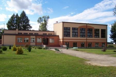 Współczesny budynek w Lini z trawnikiem, ścieżką i drzewami pod błękitnym niebem.