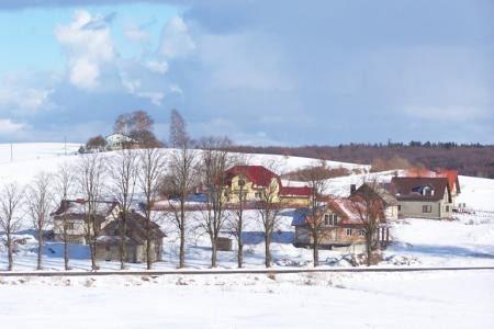 Ośnieżone domy wsi Strzepcz wśród zimowego krajobrazu.