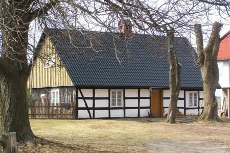 Strzepcz: Tradycyjny dom szachulcowy z gołymi drzewami.
