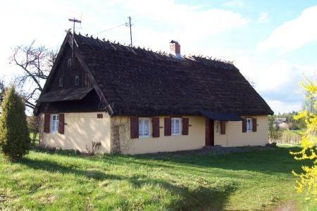 Widok na Zielony Dworek w Strzepczu, tradycyjny dom z ciemnym dachem na wzgórzu.