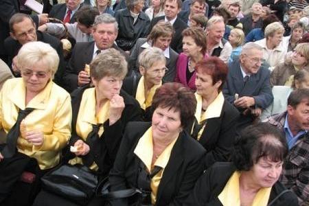 Uczestnicy Dożynek 2007, głównie kobiety w czarno-żółtych strojach, siedzą w tłumie.