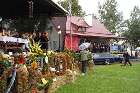 Wieńce dożynkowe i ludzie przy scenie podczas Dożynek Gminnych.