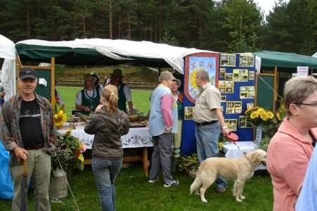 Ludzie i pies na Dożynkach Gminnych 2008 w plenerze przy stoiskach.