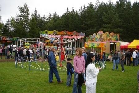 Uczestnicy Dożynek Gminnych 2008 na zielonej łące z wieńcami i sceną.