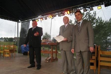 Trzech mężczyzn na scenie, jeden z dokumentem, podczas Dożynek Gminnych 2008.