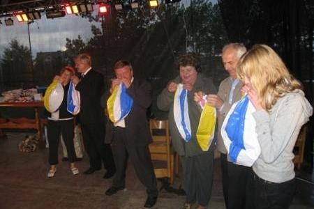 Grupa osób prezentuje kolorowe rekwizyty podczas Dożynek Gminnych 2008.