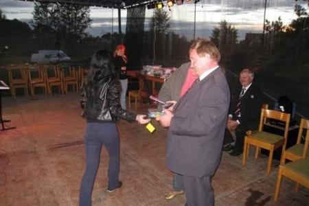 Dwóch mężczyzn wymienia jasny dar podczas Dożynek Gminnych 2008 wieczorem.