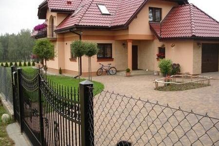 Piękny dom jednorodzinny z podjazdem i ogrodzeniem, typowy dla wiejskiego krajobrazu.