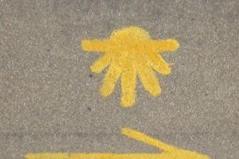 Żółta muszla pielgrzymia nad strzałką wskazującą kierunek na Drodze Francuskiej.