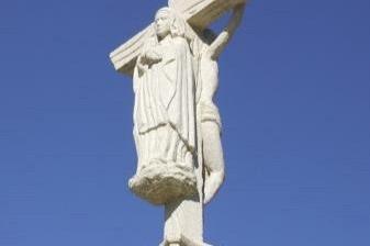 Kamienny monument z krzyżem na szczycie, na tle błękitnego nieba, na Drodze Jakubowej.