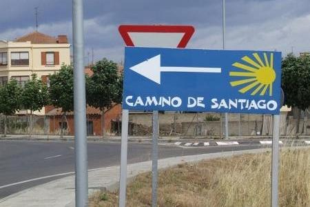 Niebieski znak Drogowego Szlaku Jakubowego ze strzałką i muszlą prowadzący do Santiago.