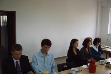 Osoby siedzą przy stole, uczestnicząc w spotkaniu lub ceremonii wręczenia stypendiów.