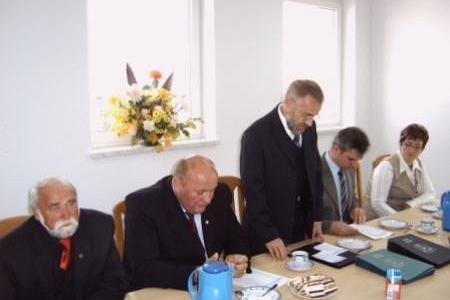 Uczestnicy ceremonii wręczenia stypendiów przy stole, jeden mężczyzna stoi.