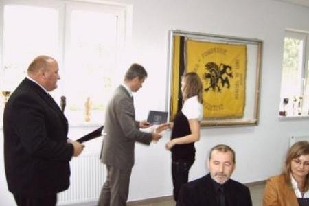 Mężczyzna wręcza dyplom kobiecie, obok stoją inni uczestnicy uroczystości stypendialnej.