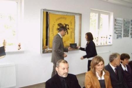 Wręczenie stypendium studentowi przez urzędnika na oficjalnej uroczystości z udziałem gości.