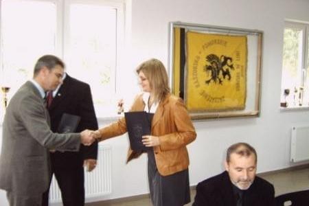 Przekazanie stypendiów dla studentów, z uściskiem dłoni oraz wymianą dokumentów.