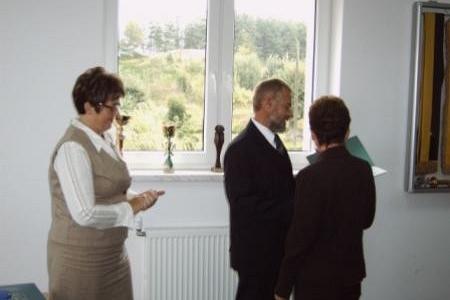 Uczestnicy wręczenia stypendiów rozmawiają w jasnym pomieszczeniu przy oknie.