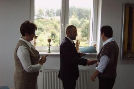 Oficjalne wręczenie stypendium studentowi, uścisk dłoni, trójka osób.