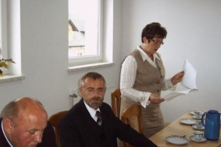 Kobieta w kamizelce przemawia podczas wręczenia stypendiów, mężczyźni słuchają.