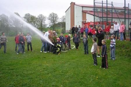 Pokaz OSP Strzepcz: strażacy leją wodę z armatki, publiczność obserwuje.