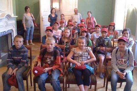 Grupa dzieci z gminy Dwikozy na kolonii pozuje do zdjęcia w sali.
