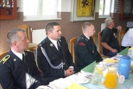 Uczestnicy Zjazdu OSP 2011 w mundurach siedzą przy stole.