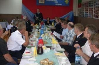 Zebrani członkowie OSP siedzą przy suto zastawionych stołach podczas zjazdu.