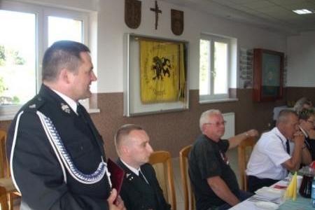 Zjazd OSP 2011: strażak w mundurze przemawia, uczestnicy siedzą przy stole.