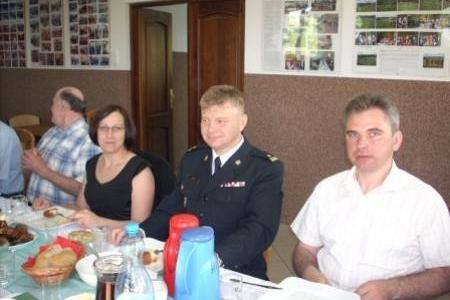 Uczestnicy Zjazdu OSP 2011 siedzący przy stole, w tym mężczyzna w mundurze.