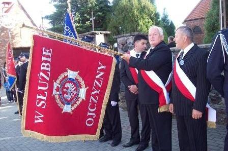Członkowie OSP Lewino w mundurach prezentują sztandar jednostki podczas uroczystości.