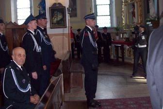 Członkowie OSP Lewino w kościele podczas uroczystości, w tle ławki i okna.