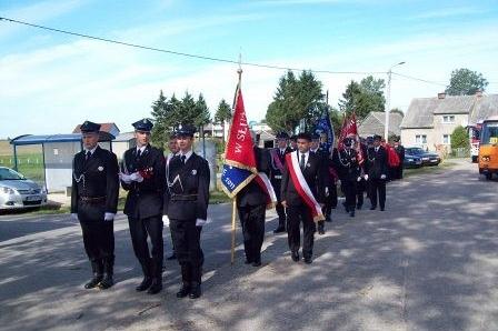 Strażacy OSP Lewino w galowych mundurach z sztandarem podczas uroczystości.