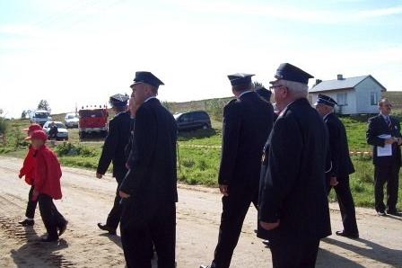 Strażacy OSP Lewino z dzieckiem podczas uroczystości pod gołym niebem.